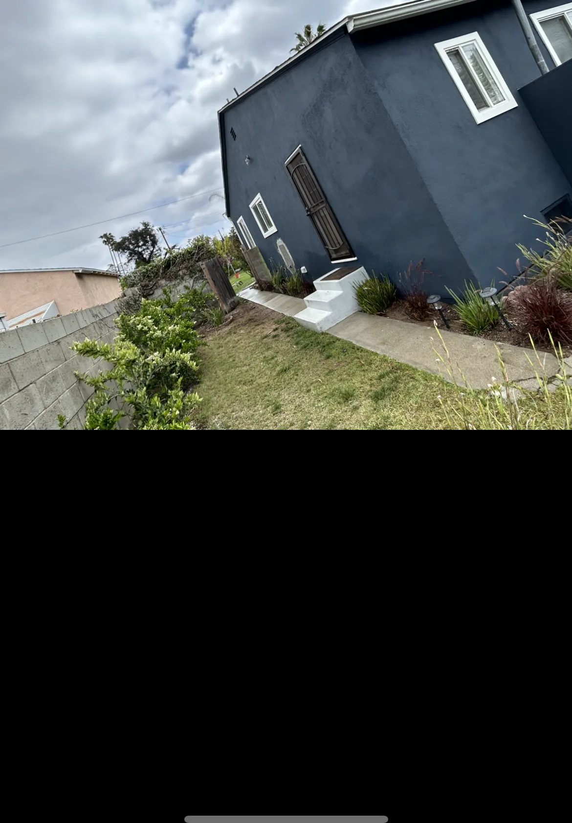 Dark blue stucco exterior with fresh landscaping