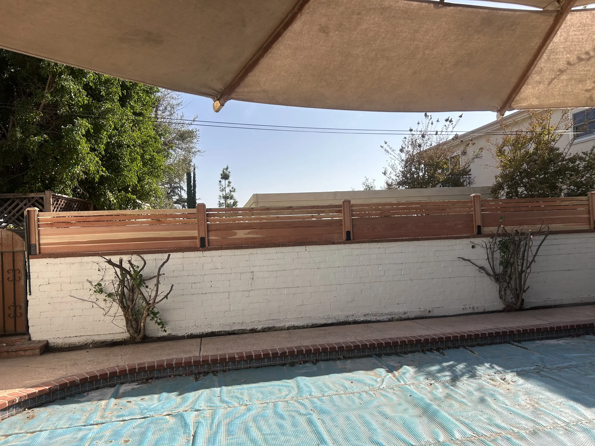 Cedar fence topper with shade sail over patio area