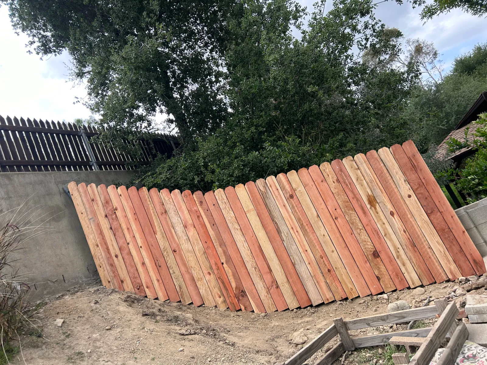 Dog-ear cedar fence atop a retaining wall on sloped property
