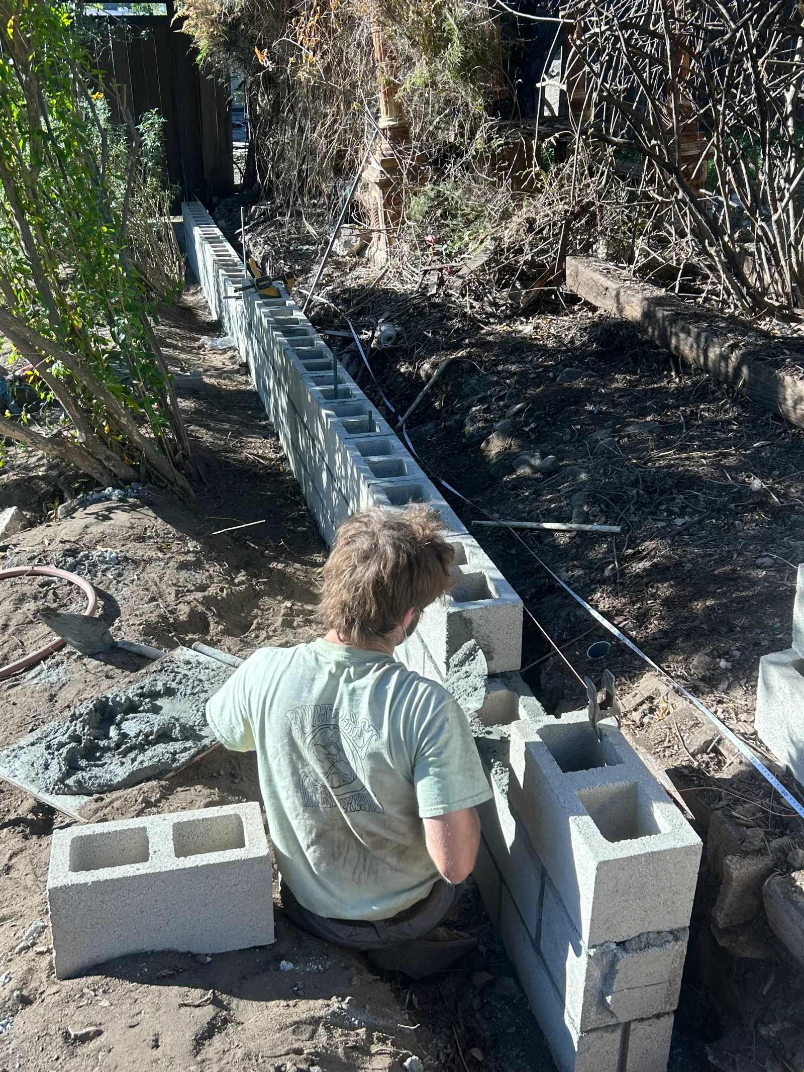 Ryan setting cinder blocks for a retaining wall on a hillside property